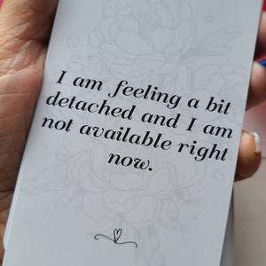 May include: A white card with a floral design and the text "I am feeling a bit detached and I am not available right now."