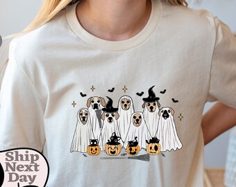 Puede incluir: Una camiseta blanca con un gráfico de perros disfrazados de fantasmas para Halloween. Los perros llevan sombreros de bruja y sostienen calabazas. El texto "Ship Next Day" es visible en la esquina inferior izquierda de la imagen.