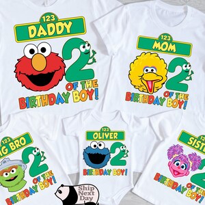 Puede incluir: Camisetas blancas con dise&ntilde;os de personajes de Barrio S&eacute;samo para una familia. Las camisetas presentan a Elmo, Big Bird, Cookie Monster, Oscar y Zoe, con textos que dicen "Daddy", "Mom", "Big Bro", "Oliver" y "Sister". Cada camiseta tiene el n&uacute;mero 2 y "Birthday Boy!"