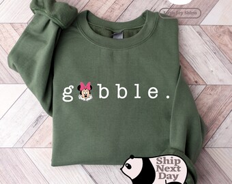 May include: Green sweatshirt with white text that says "gobble." A cartoon image of Minnie Mouse is in the "g".