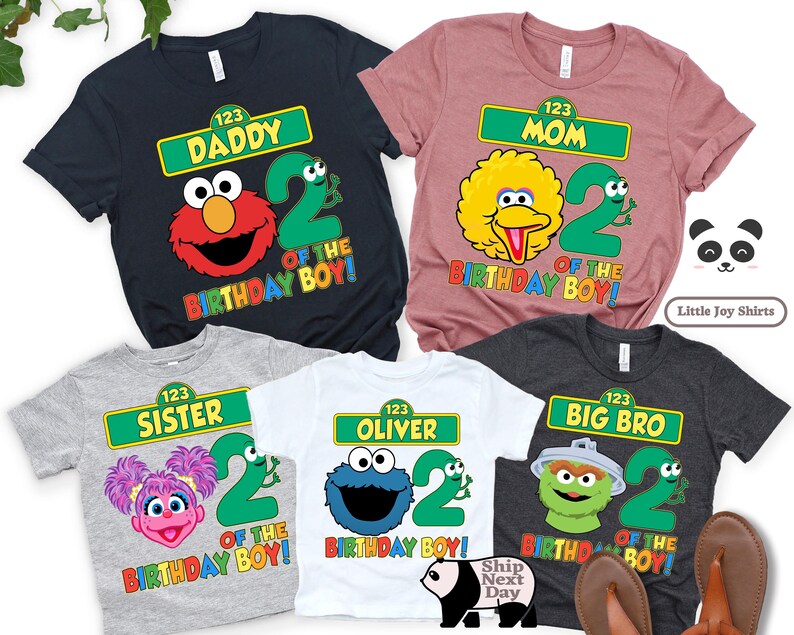 Puede incluir: Varios camisetas coloridas con personajes de Barrio S&eacute;samo y el n&uacute;mero 2. Cada camiseta tiene un dise&ntilde;o diferente, incluyendo "Daddy", "Mom", "Sister", "Oliver" y "Big Bro", con el texto "Of The Birthday Boy!"
