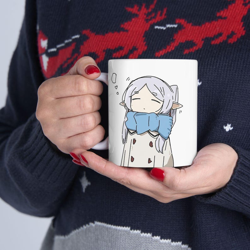 May include: White ceramic mug with a cartoon illustration of a girl with long white hair wearing a blue scarf and a white coat. The girl has closed eyes and a sleepy expression.