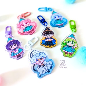 May include: Set of six colorful cartoon character keychains with a whimsical design. Each keychain features a different character wearing a pointed hat and a colorful outfit. The keychains are made of clear acrylic and have a metal ring for attaching to keys or bags.
