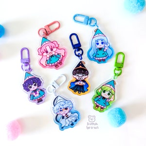 May include: Seven colorful character charms with keychains. Each charm features a different anime-style character wearing a hat and a green outfit. The charms are made of clear acrylic and have a glossy finish.