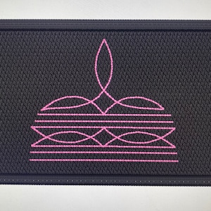 Könnte beinhalten: Eine rechteckige schwarze Fußmatte mit einem rosafarbenen geometrischen Muster. Das Muster besteht aus einer Reihe von geschwungenen Linien und einem zentralen Punkt.