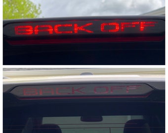 以下が含まれることがあります： 太字で「BACK OFF」という文字を表示する赤いLEDライトバー。 ライトバーは、黒いハウジングを備えた車両の後部に設置されています。