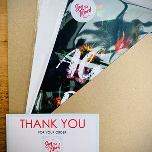 May include: An art print with a floral design is packaged with a thank you card. The print is sealed in a clear plastic sleeve and placed inside a cardboard envelope. The thank you card has the text "THANK YOU FOR YOUR ORDER".
