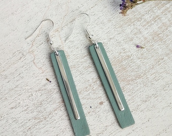 May include: A pair of silver and sage green dangle earrings. The earrings are made of leather and have a silver bar running down the center.
