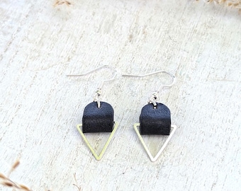 May include: A pair of black leather earrings with gold triangle accents. The earrings are hanging from silver hooks.