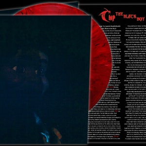 May include: A red vinyl record with a black and white image of a person's face on the cover. The text "The Black Boy" is printed on the cover.