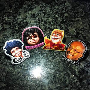Peut inclure: Quatre boutons à épingle colorés représentant des portraits de célébrités. Les boutons représentent Chip the Black Boy, Marcama, Jason the Cat et David Letterman.