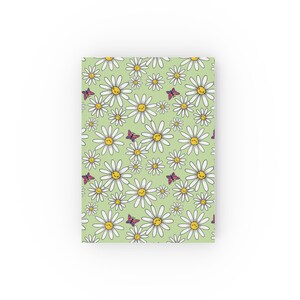 May include: A green background with a repeating pattern of white daisies with yellow centers and smiling faces.  Purple butterflies are scattered throughout the pattern.