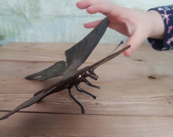 May include: A metal butterfly sculpture with brown and green wings. The sculpture is made of wire and has a rustic finish.