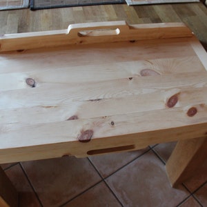 May include: A light wood serving tray with a handle and two cutouts on the underside. The tray is made of natural wood with knots and grain patterns.