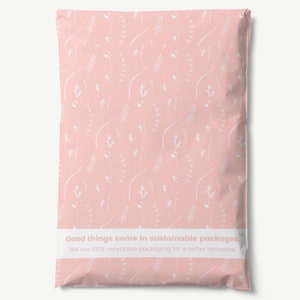 May include: Pink poly mailer with a white floral pattern. The mailer has a white label with the text "Good things come in sustainable packages. We use 100% recyclable packaging for a better tomorrow. TM"