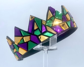 May include: A crown made of black felt with a mosaic of green, purple, and gold mirror tiles.