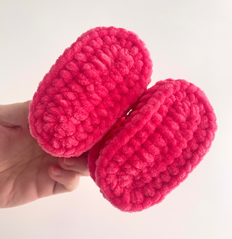 May include: A pair of pink crocheted baby booties. The booties are made with a soft, fuzzy yarn and have a simple, classic design.