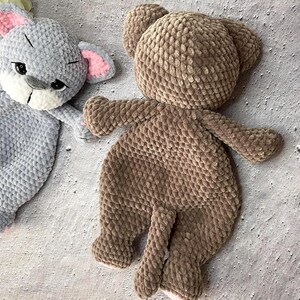 May include: Two handmade plush toys: a gray bunny with pink ears and a brown bear. The bunny has black eyes and a white muzzle. The bear has a round head, small ears, and a tail. Both toys are made of a soft, textured material.