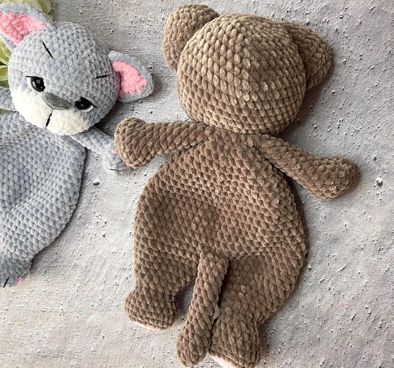 May include: Two handmade plush toys: a gray bunny with pink ears and a brown bear. The bunny has black eyes and a white muzzle. The bear has a round head, small ears, and a tail. Both toys are made of a soft, textured material.