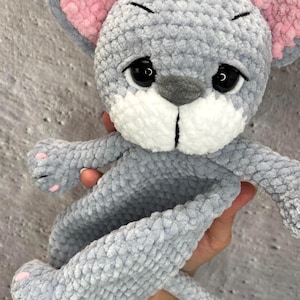 May include: A handmade gray crochet mouse plush toy with pink inner ears and paw pads. The mouse has black eyes and a white muzzle. The toy is soft and cuddly, perfect for children.