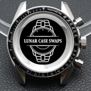 May include: A stainless steel watch case with a black and white tachymeter bezel. The watch face displays the text "LUNAR CASE SWAPS" in white on a black background, encircled by a watch outline.