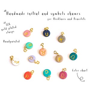 May include: Assortment of handmade initial and symbol charms for necklaces and bracelets. The charms are made of polymer clay and feature gold-plated clasps. The charms are hand-painted with various colors and designs, including letters, zodiac signs, and other symbols.