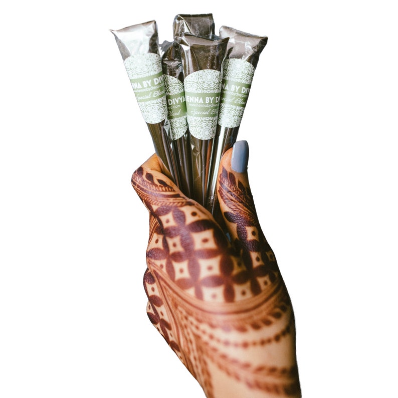 May include: A hand with henna designs holds a bundle of five brown henna cones with white labels that read "DIYENNA BY DIVYA Special Blend"