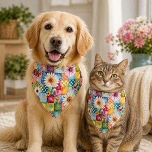 May include: A golden retriever and a tabby cat sitting side by side, both wearing matching triangular pet bandanas. The fabric features a colourful patchwork design with various floral patterns, including white daisies, pink blossoms, and blue polka dots.