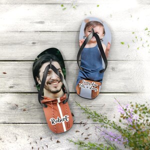 May include: A pair of custom flip-flops featuring black straps. One flip-flop displays a portrait of a person in an orange jacket with the name Robert printed in white. The other flip-flop shows a child in a blue outfit with the text Every step tells a story.