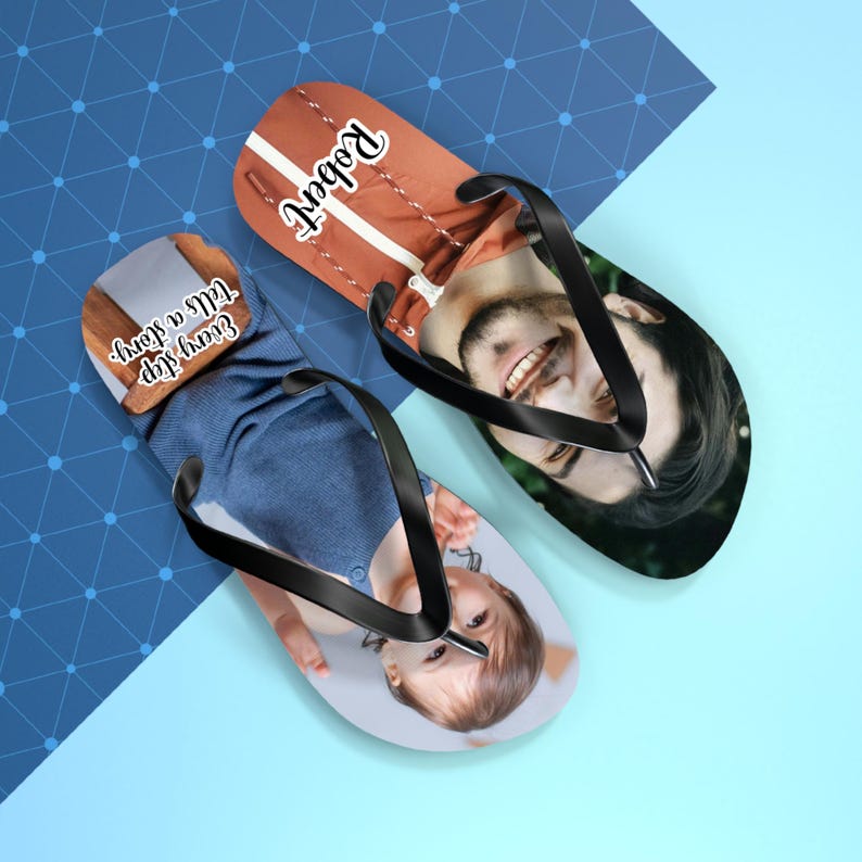 May include: A pair of custom flip-flops with black straps. One flip-flop features a photo of a smiling man and the name Robert in white script. The other flip-flop displays a photo of a child and the text Every step tells a story in white script.