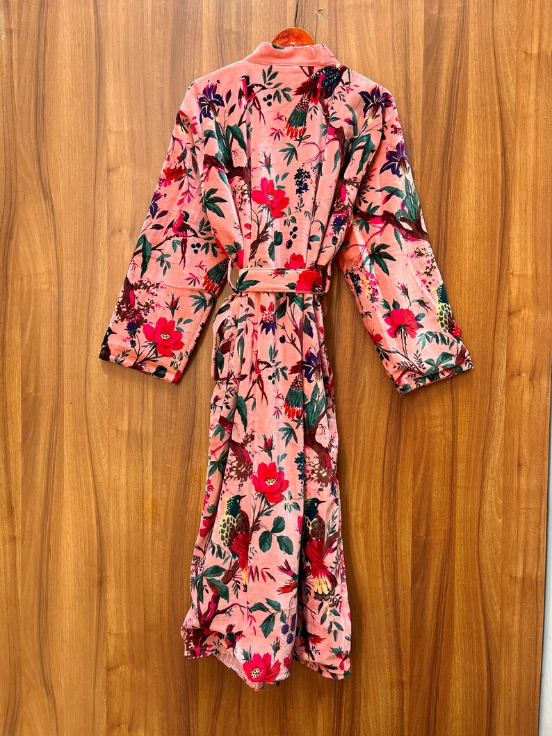 Peut inclure: Une robe en velours rose avec un imprim&eacute; floral et d'oiseaux. La robe a une ceinture &agrave; nouer et des manches longues.