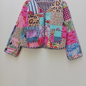 May include: A quilted jacket featuring a patchwork design with various patterns including leopard print, floral motifs, stripes, and lobster illustrations. The jacket has a V-neckline, long sleeves, two front pockets, and a button-front closure.