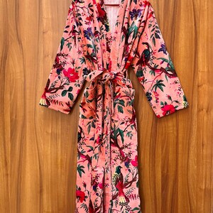 Peut inclure: Une robe en velours rose avec un imprim&eacute; floral et d'oiseaux. La robe a une ceinture &agrave; nouer et deux poches.