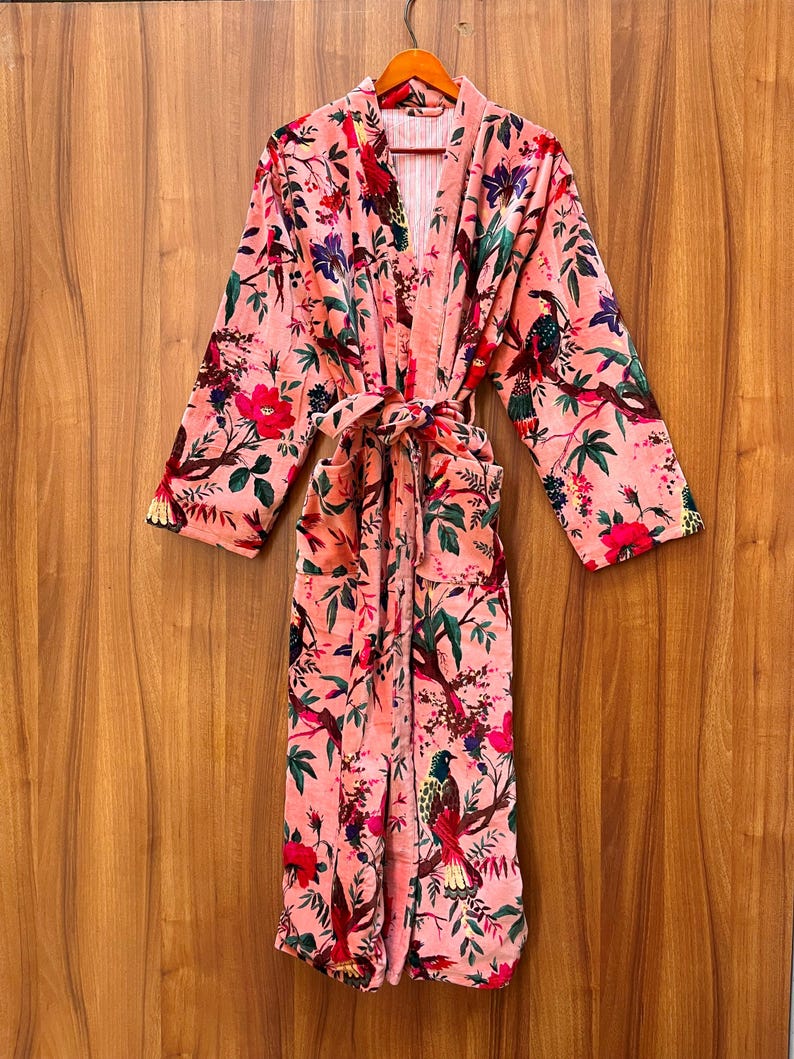 Peut inclure: Une robe en velours rose avec un imprim&eacute; floral et d'oiseaux. La robe a une ceinture &agrave; nouer et deux poches.