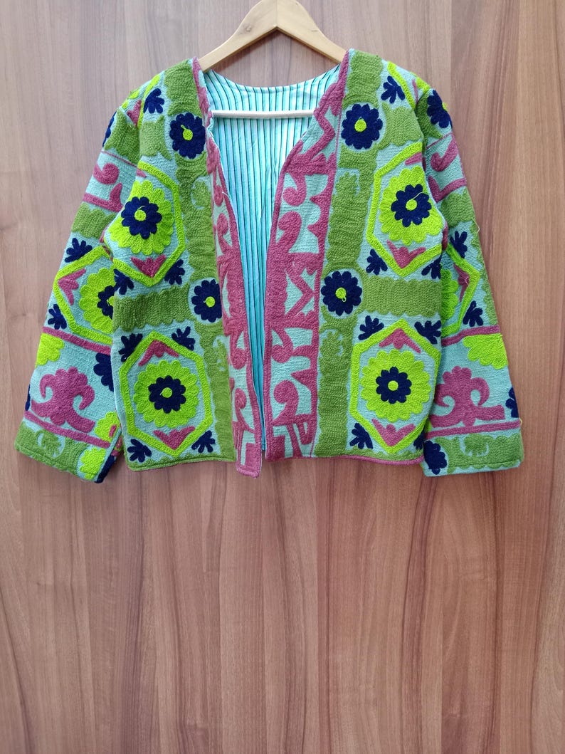 May include: A green, blue, and pink embroidered jacket with floral patterns. The jacket has a V-neck and long sleeves.