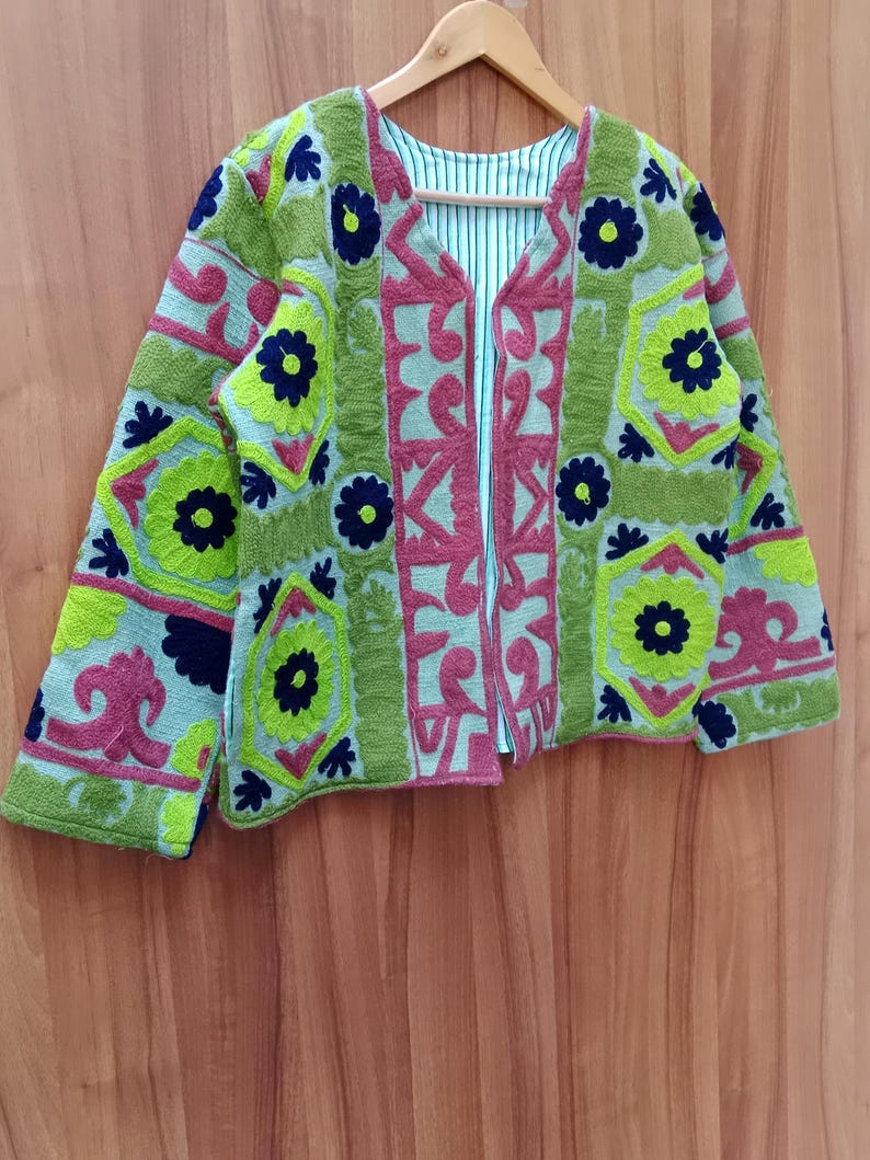 May include: A green, pink, and blue embroidered jacket with floral patterns. The jacket has a V-neck and long sleeves.