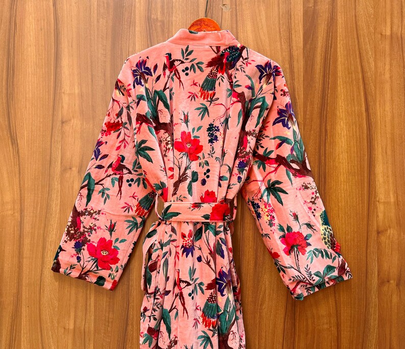 Peut inclure: Une robe en velours rose avec un imprim&eacute; floral et d'oiseaux. La robe a une ceinture &agrave; nouer et des manches longues.