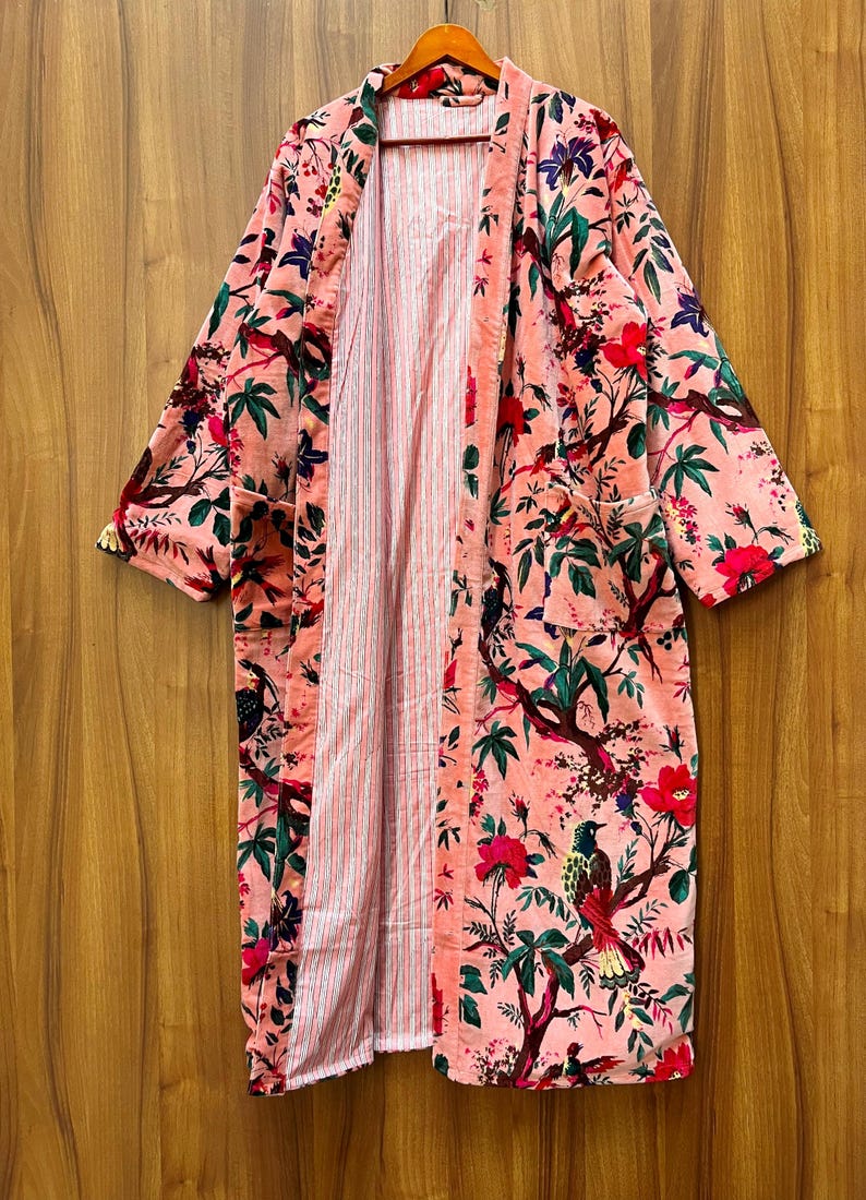 Peut inclure: Une longue robe de chambre rose &agrave; imprim&eacute; floral avec une doublure ray&eacute;e. La robe a un col large et des manches longues.