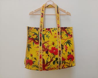 May include: Yellow tote bag with a floral print featuring red flowers and birds. The bag has a yellow and white trim around the edges.