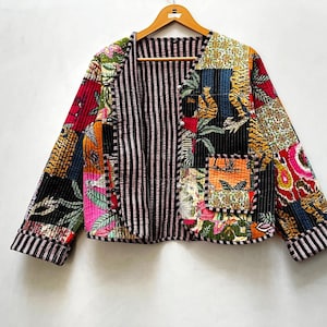 May include: A patchwork jacket with a variety of colorful patterns, including floral, tiger stripe, and geometric designs. The jacket has a black and white striped interior and is hanging on a wooden hanger.