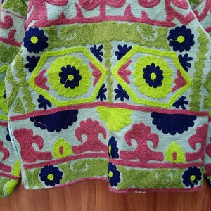 May include: A green, pink, and blue embroidered jacket with floral and geometric patterns.