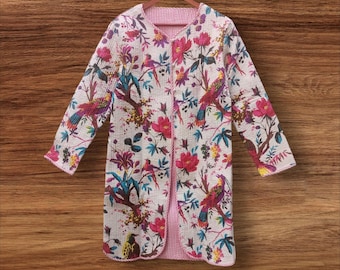 Puede incluir: Una chaqueta larga y abierta con un estampado floral y de pájaros vibrante. La chaqueta presenta un fondo blanco con pájaros coloridos, flores rosas y hojas verdes. El forro interior es de tela a rayas rosas y blancas.