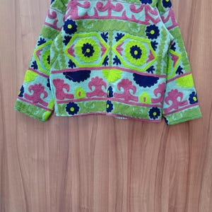 May include: A green, blue, pink, and yellow embroidered jacket with floral and geometric patterns.