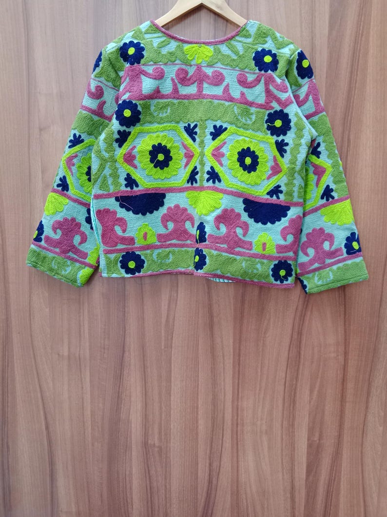 May include: A green, blue, pink, and yellow embroidered jacket with floral and geometric patterns.