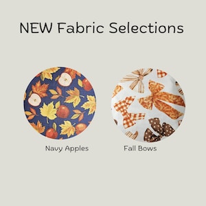 May include: NEW Fabric Selections text above two circular fabric swatches. The left swatch is navy blue with red apples and yellow autumn leaves. The right swatch is white with orange and brown patterned bows labeled Navy Apples and Fall Bows.