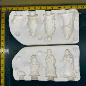 Puede incluir: Moldes de cerámica blanca para hacer figuras de la natividad. Los moldes están en dos piezas y muestran las figuras de los tres reyes magos, un pastor, un cordero y una estrella.