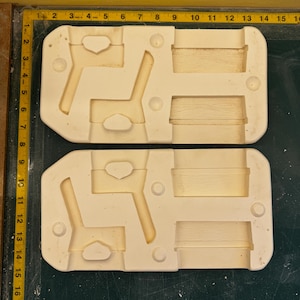 Puede incluir: Dos moldes de cerámica blanca para fundir artesanías de resina. Los moldes están divididos en dos secciones, cada una con dos formas de silla y dos formas rectangulares.