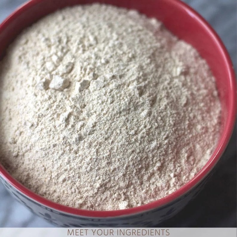 May include: A close-up view of a red bowl filled with a white powder, likely flour. The bowl has a floral pattern around the rim.