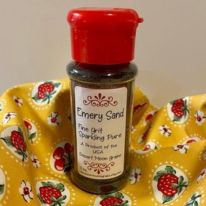 K&ouml;nnte beinhalten: Ein kleines Glas mit rotem Deckel, gef&uuml;llt mit braunem Schmirgelsand. Das Etikett lautet "Emery Sand Fine Grit Sparkling Pure A Product of the USA Desert Moon Grains 5 oz www.desertmoongrains.etsy.com"