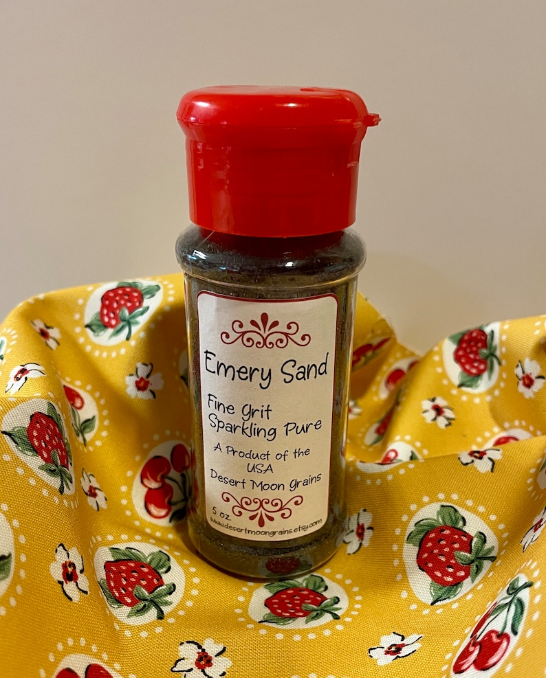 K&ouml;nnte beinhalten: Ein kleines Glas mit rotem Deckel, gef&uuml;llt mit braunem Schmirgelsand. Das Etikett lautet "Emery Sand Fine Grit Sparkling Pure A Product of the USA Desert Moon Grains 5 oz www.desertmoongrains.etsy.com"